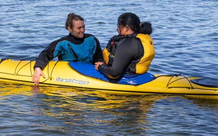 an instructor gives direction to a student in a kayak on an outward bound trip